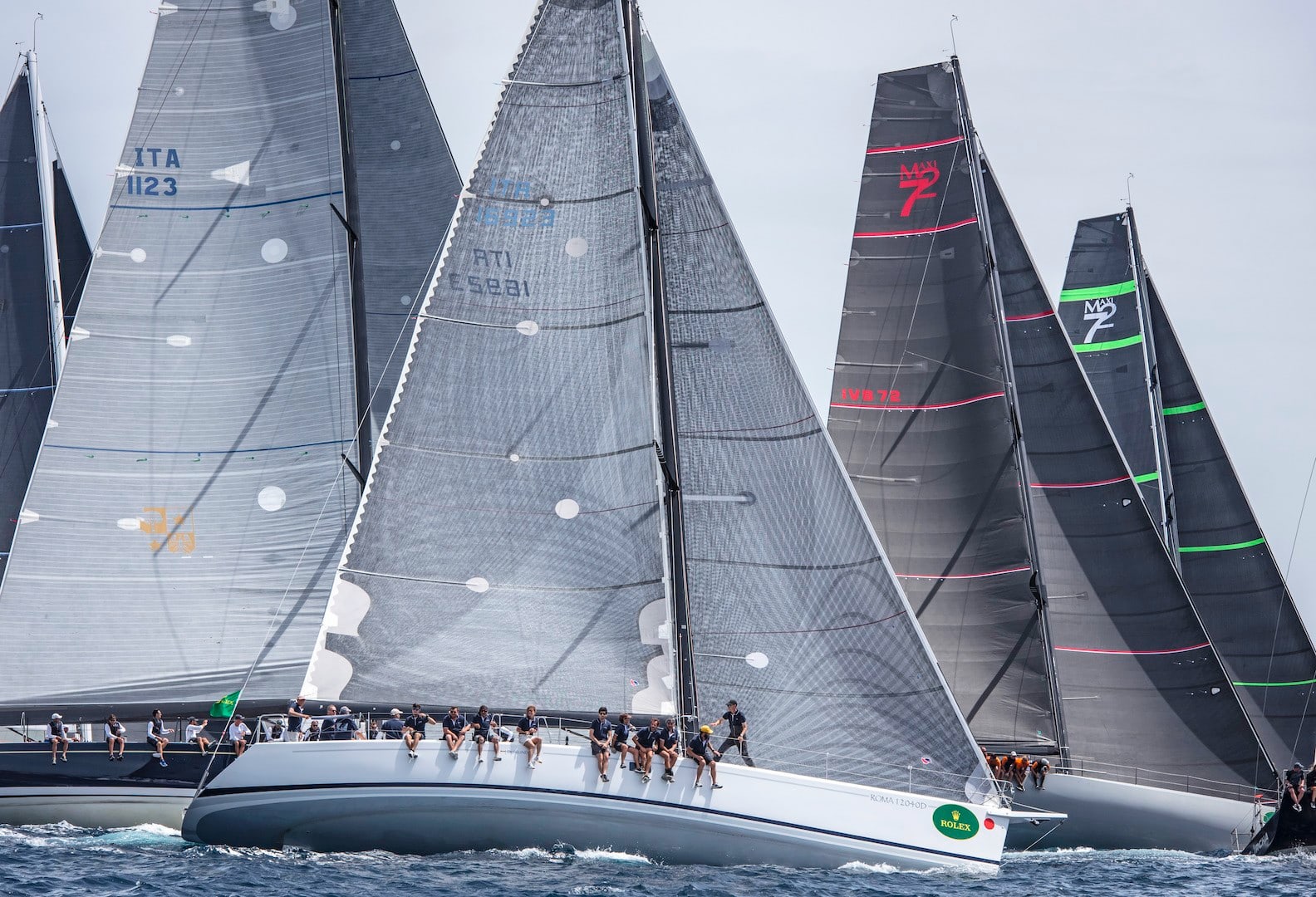 Flotte de maxi yachts au près serré en Méditerranée pendant une course du Rolex Giraglia — voiliers Farr 60 et Maxi 72, sail numbers ITA 1123, ITA 16923, ITA 12, MAXI 72 visibles.